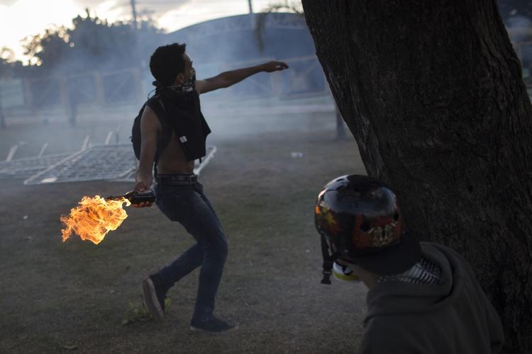 Uro. En demonstrant kaster en Molotov-cocktail mod politiet, nær Mineirao-stadionet inden aftenens kamp. 