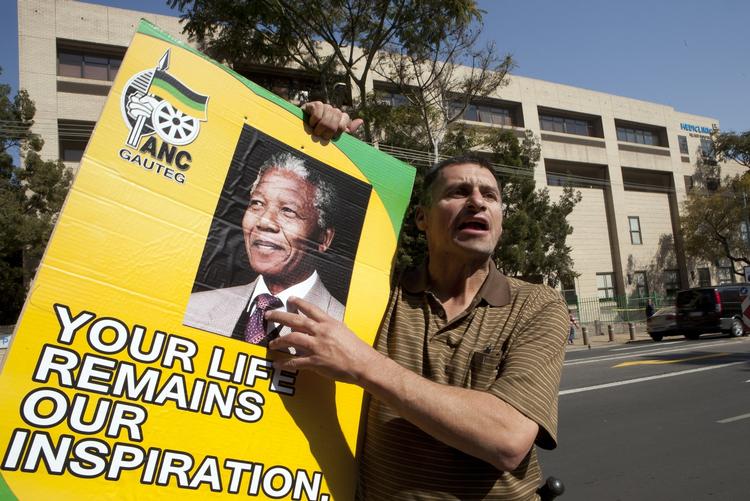 Støtte. En sydafrikaner holder en plakat for partiet ANC, som Mandela tilhører, uden for hospitalet hvor den tidligere præsident har ligget siden juni måned. 