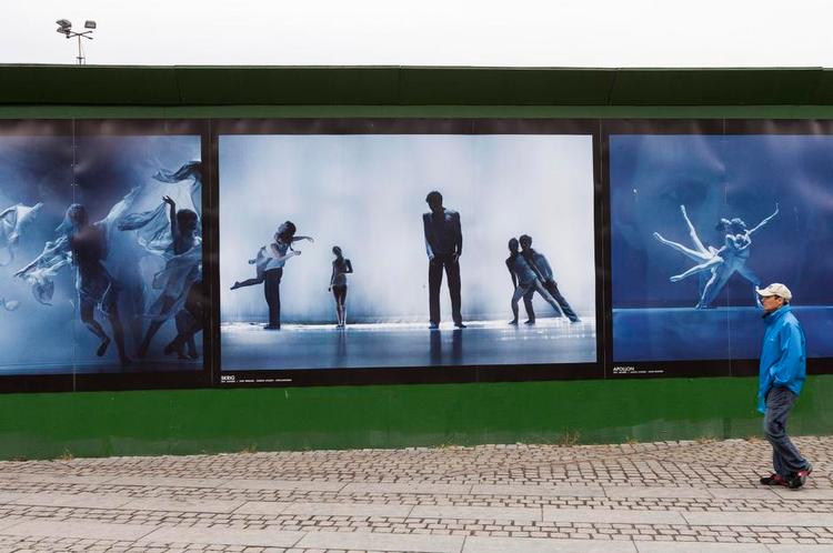 Tilfælde. Hvor er det betænksomt, at manden, der passerer forbi Ingrid Bugges balletfotografier, har taget en blå regnfrakke på. For den står perfekt til Bugges blånende optagelser fra balletscenens rum, med al deres magiske lys, dybe mystik og elegante bevægelser. 