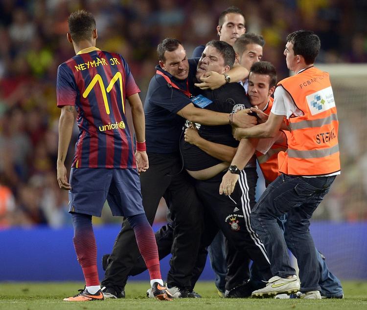 blodmangel. Neymar (tv) ser bekymret til, mens sikkerhedsfolk forsøger at stoppe en baneløber under kampen mellem Barcelona og Santos. 