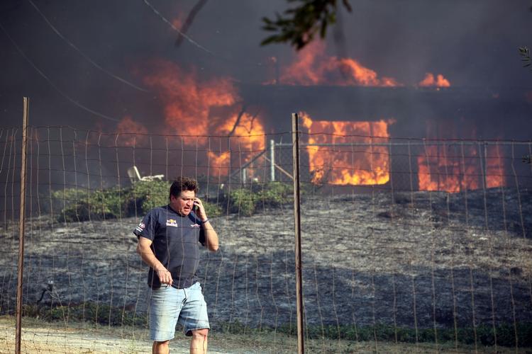 STORBRAND. David Clarke fra byen Twin Pines taler i telefon ud for sit brændende hjem, en af de mange boliger, der er gået til under en omfattende naturbrand i det sydlige Californien. 