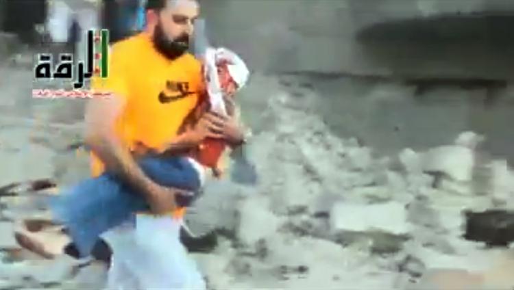 BORGERKRIG. Syrisk mand bærer såret barn væk efter missilangreb mod byen Raqqa i går. Billedet stammer fra Shaam News network, men ægtheden er bekræftet af nyhedsbureauet AP's fotoafdeling. 