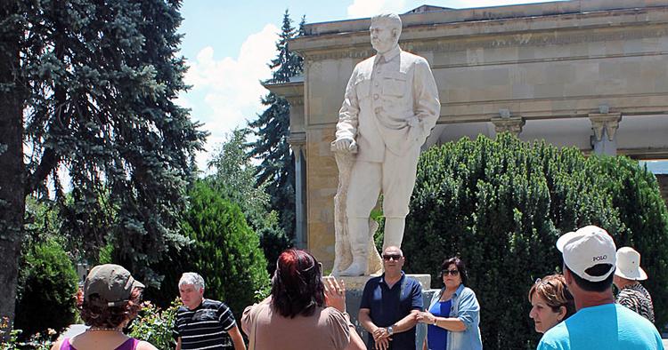 FASCINATION Turister stiller op til fotografering sammen med statuen af Stalin. Bagved ses bygningen, som er opført uden om hans fødehjem. Resten af det fattige kvarter er revet ned. 