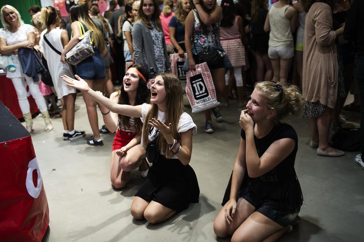 BOYBANDKÆRLIGHED. Pigerne ligger på knæ og tilbeder storskærmen, der viser musikvideoer med boybandet One Direction. Foto: DITTE VALENTIN 