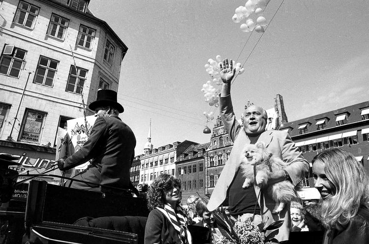 1981 Simon Spies fejrede sin 60 års fødselsdag med bl.a. en karettur gennem København. Balloner sendes til vejrs og Spies vinker fra sin karet. I favnen har han hunden Archibald. 
