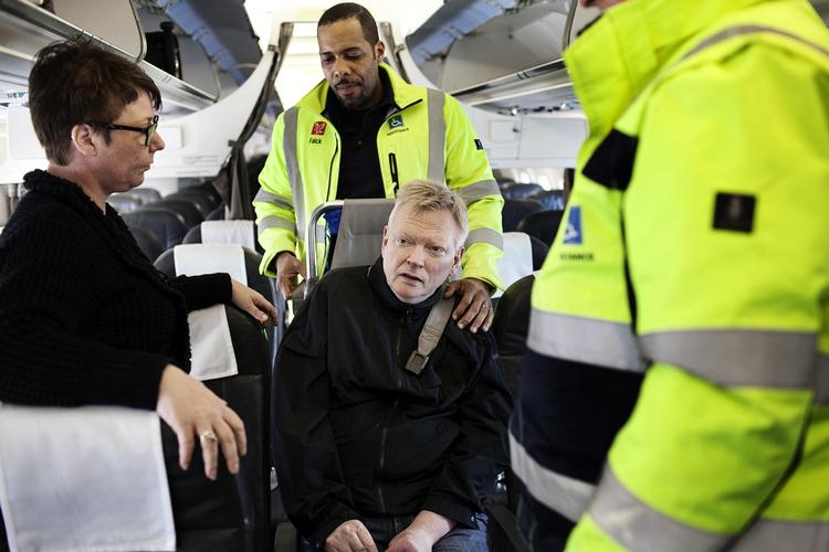 Assistance. To Falck-ansatte hjælper Stig Langvad til rette i flysædet. Han er handicappet og kan ikke klare sig selv på en flytur. 