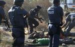 POLITIAKTION. Betjente ved nogle af de strejkende minearbejdere under sammenstødene ved Lonminminen nær Marikana. 