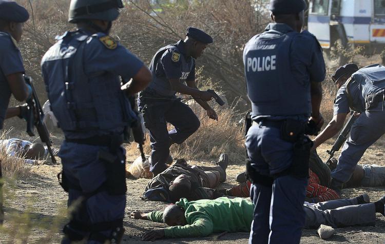 POLITIAKTION. Betjente ved nogle af de strejkende minearbejdere under sammenstødene ved Lonminminen nær Marikana. 