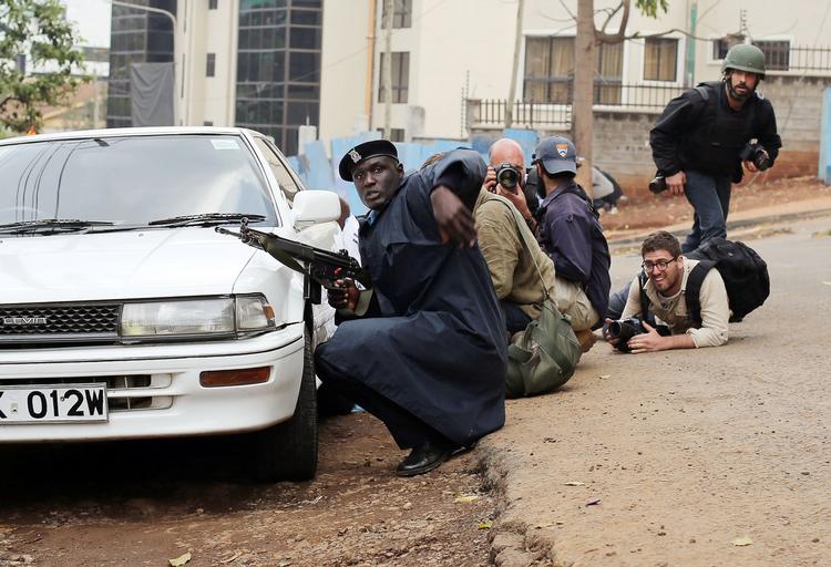 Redningsaktion. Kenyanske sikkerhedsstyrker og journalister dukker sig bag et køretøj under en skudveksling med gidseltagerne i bygningen Westgate. Billede fra i går. 