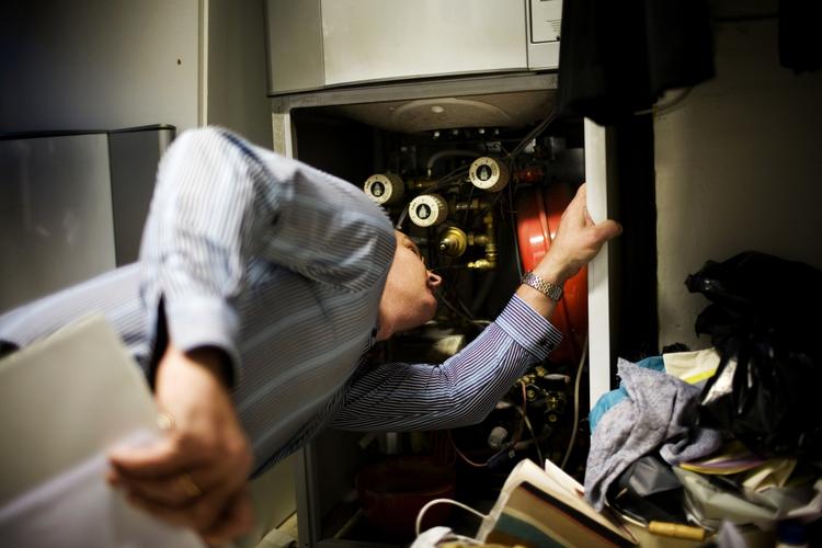 koldt. Energikonsulent tjekker varmeanlæg. Selv med lunkne radiatorer kan varmeregningen blive høj, hvis systemet ikke fungerer optimalt. 