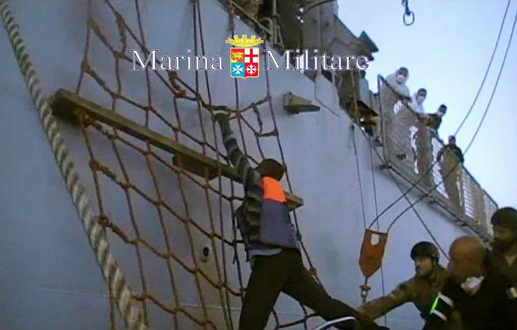 Migration. En bådflygtning hjælpes ombord på et italiensk krigsskib. Billedet stammer fra optagelser fra det italienske militær. (arkiv) 