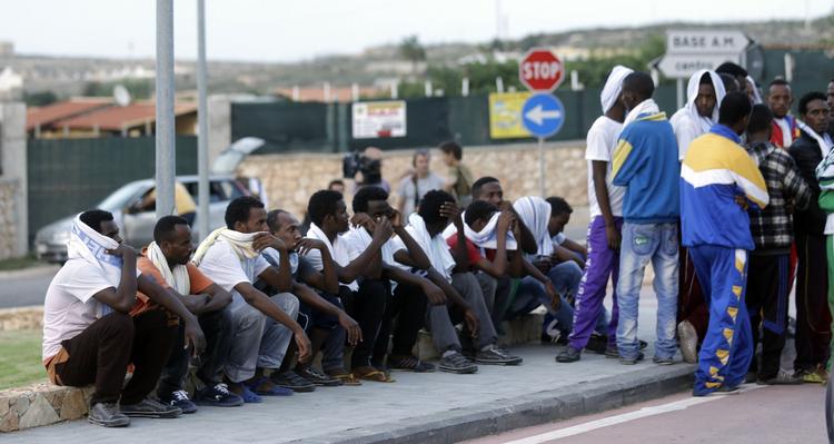 Forlis. Migranter fra Eritrea venter uden for en lufthavnshangar med kisterne med de skibbrudne på øen Lampedusa, Italien. 