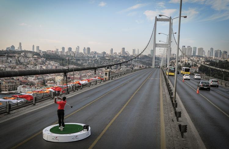 verdensdele. Tiger Woods skyder golfbolde fra øst til vest over den berømte bro over Bosporus-strædet. 
