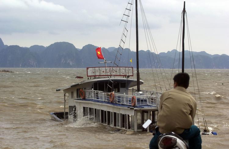 Tyfon. En mand betragter en synkende turistbåd i Ha Long Bay i Vietnam, hvor tyfonen, der har dræbte mange i Filippinerne i morges gik i land. 