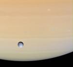 Saturn ledsages af adskillige drabanter (måner). Den følges på sin færd rundt om Solen af over 60 måner. Her er det Dione, der er fotograferet svævende over gasplanetens overflade af Cassini-sonden. 