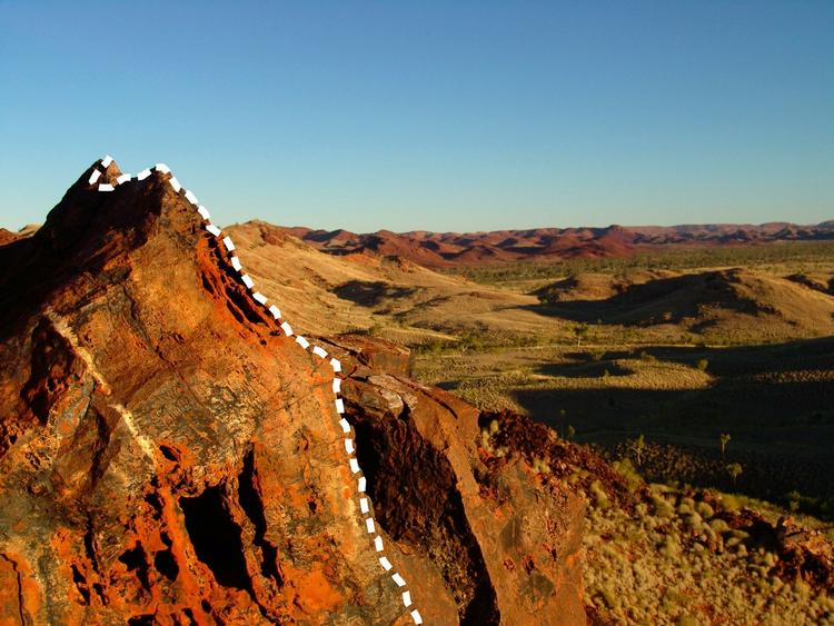 FUNDSTED. Pilbara-området er et yndet sted for forskere på jagt efter fossiler fra det tidlige liv. Den hvide streg på klippen viser forsteningerne af 3 milliarder år gamle mikrober. 