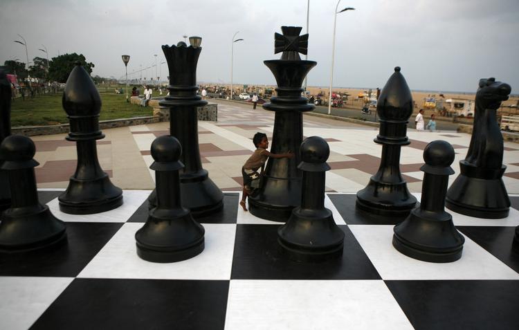 vm-opgør. En indisk dreng leger med et kæmpemæssigt skak-bræt ved kysten i Chennai, hvor VM-matchen mellem  Viswanathan Anand og Magnus Carlsen foregår. 