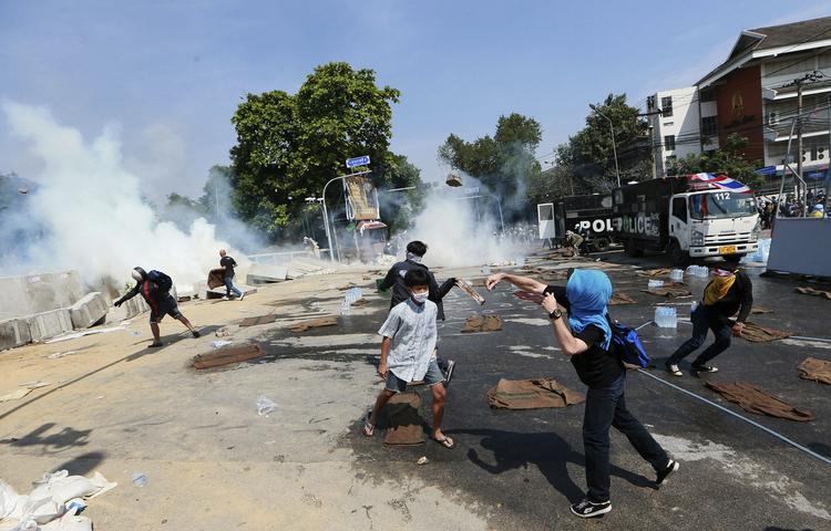 OPRØR. Demonstranter kaster sten efter politiet, som har affyret tåregas mod dem i nærheden af regeringsbygningen i Bangkok. 