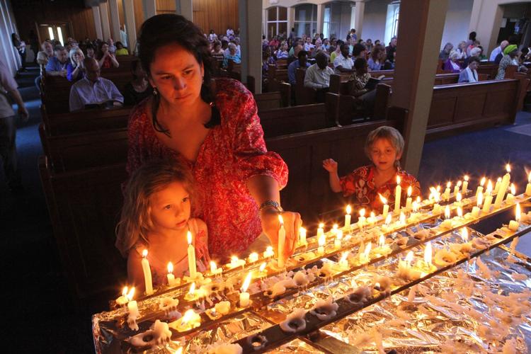 Mindedag. En mor og hendes børn tænder lys under en messe til ære for Nelson Mandela i Johannesburg. 