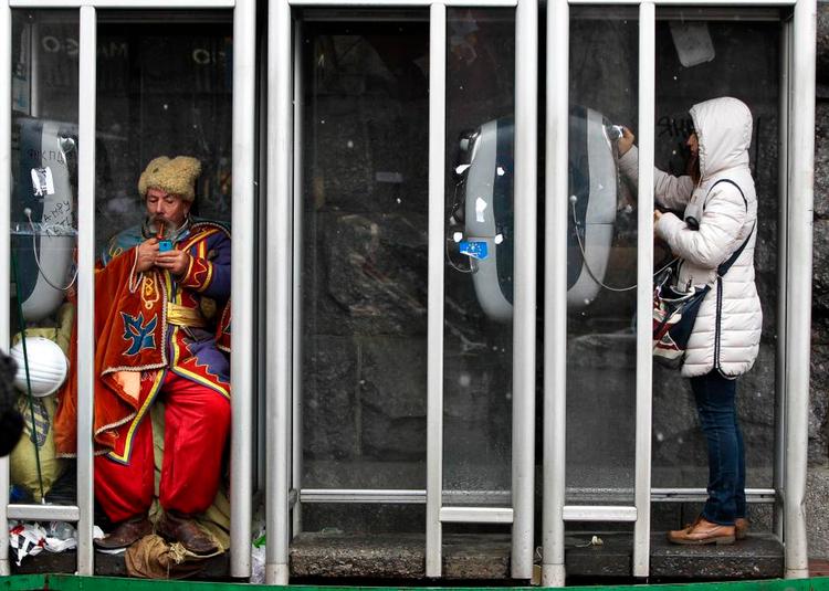 Kontraster. Modstanden mod regeringen kommer fra alle lag. En demonstrant fra mindretallet af tartarer på Krim er flyttet ind i en telefonboks under protesterne i Kijev. 