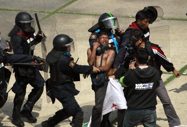 PROTEST. En regeringsfjendtlig demonstrant bliver tilbageholdt af politiet under en demonstration ved et stadium i Bangkok i dag, hvor omkring 30 partier var mødt op for at lade sig registrere til det planlagte parlamentsvalg i Thailand 2. februar 2014. Demonstranterne forlanger, at valget udskydes. 