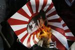 En demonstrant sætter ild til et japanske militærflag i protest over Shinzo Abes besøg i Yasakuni Templet i Tokyo. 