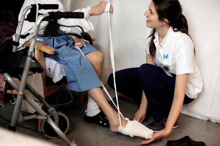 Nyuddannet. Katrine Haagensen havde som nyuddannet ergoterapeut svært ved at finde job, men et traineeforløb. Her viser hun på en patient, hvordan hun skal tage strømper på uden at belaste hoften. 