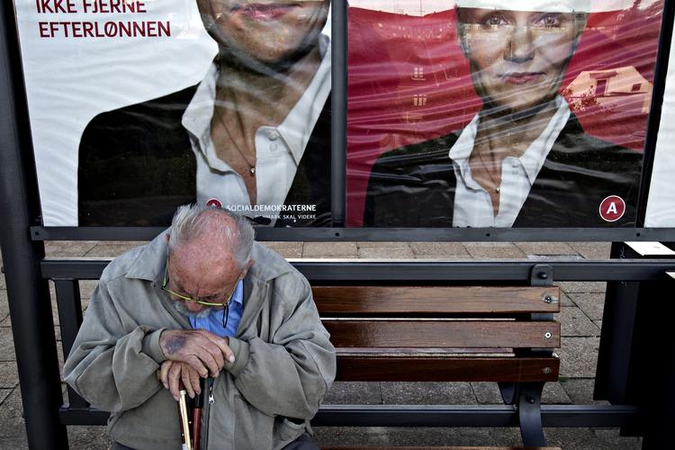 Idékrise. Her ses forhenværende statsminister Anker Jørgensen foran valgplakater på en s-togsstation. 