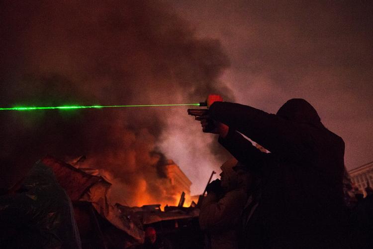 Her sigter en demonstrant med en laserpen over brændende barrikader og skyder gentagne gange mod politiet med en softgun. 