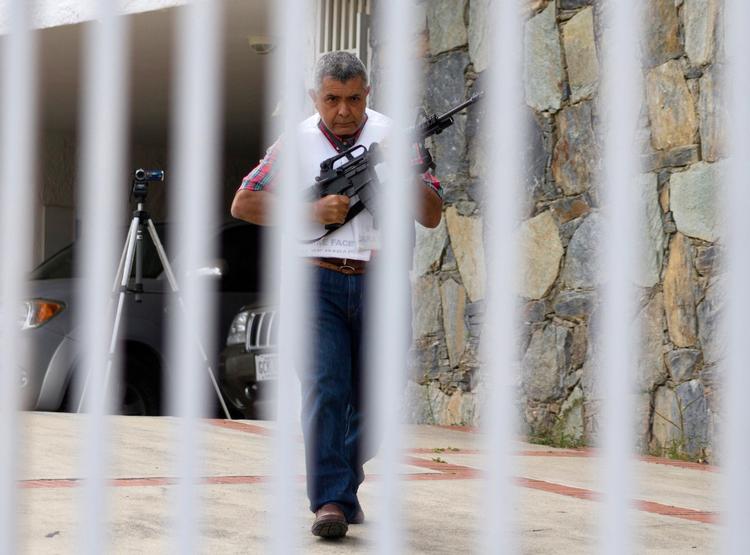 Forskanset. Tidligere general Angel Vivas går bevæbnet og med beskyttelsesvest bag sin låge søndag i Caracas. 