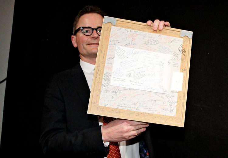 Farvel. Lars Munch med bagsiden af den afskedsgave, han fik af Politiken. Forsiden forestiller et portræt af direktøren, som Mette Dreyer har tegnet. Og på bagsiden har avisens medarbejderne skrevet hilsner. 