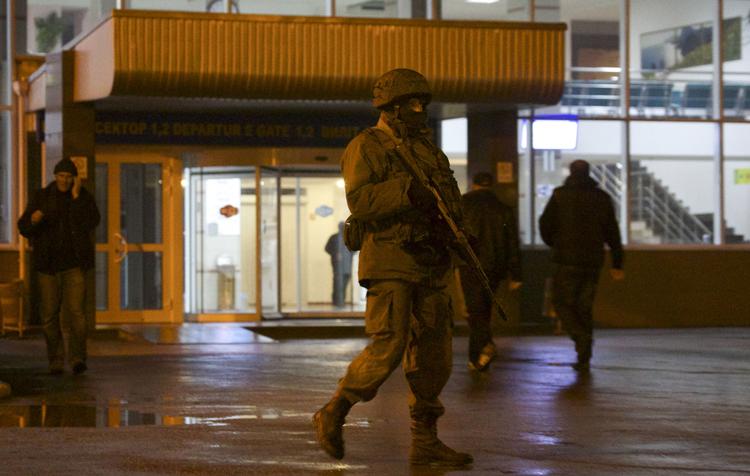 patrulje. En udentificeret bevæbnet mand patruljerer uden for den civile lufthavn Simferopol i Ukraine. 