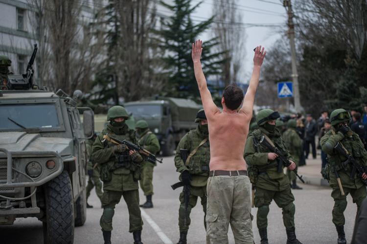 Konflikt. En ukrainsk mand har smidt overtøjet i protest mod de russiske soldater, som har taget kontrollen med store dele af Krim-halvøen. Her ses de i Balaklava i udkanten af havnebyen Sevastopol. der i forvejen er hjemsted for en stor russisk flådestyrke. 
