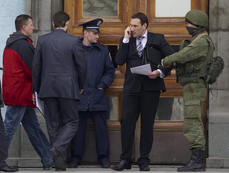 I Simferopol står en politimand og en uidentificeret bevæbnet mand vagt foran lokalregeringens bygning. 
