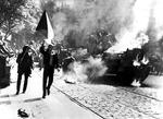 Demonstranter med et tjekkisk flag går forbi en brændende kampvogn på en gade i Prag. 