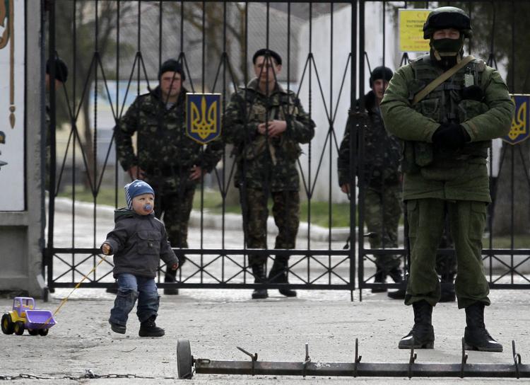 Internationalt. Et lille barn leger midt blandt ukrainske og russiske tropper ved en militærbase i Ukraine. 