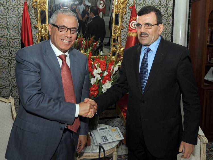 Tunesiens ministerpræsident Ali Larayed (th.) giver hånd til Libyens nu tidligere ministerpræsident Ali Zeidan (tv.) i en lufthavn i tunesien. 