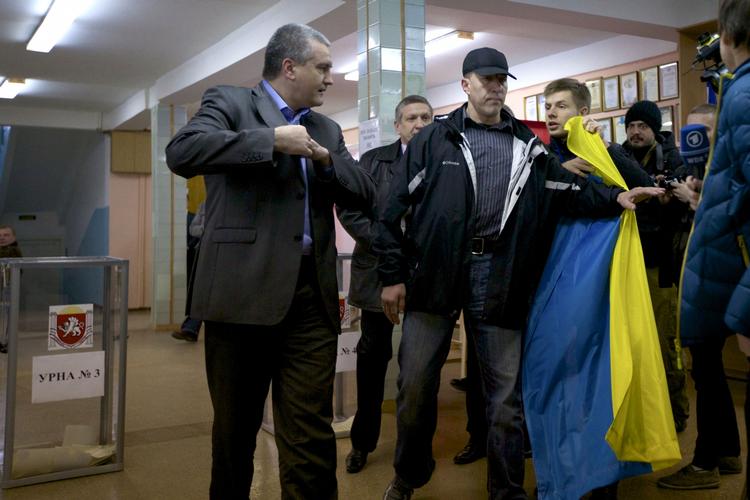 AFSTEMNING. Mand med det ukrainske flag holdes tilbage ved et valgsted, mens lederen af den lokale regering på halvøen, Sergej Aksyonov, besøger stemmested. 