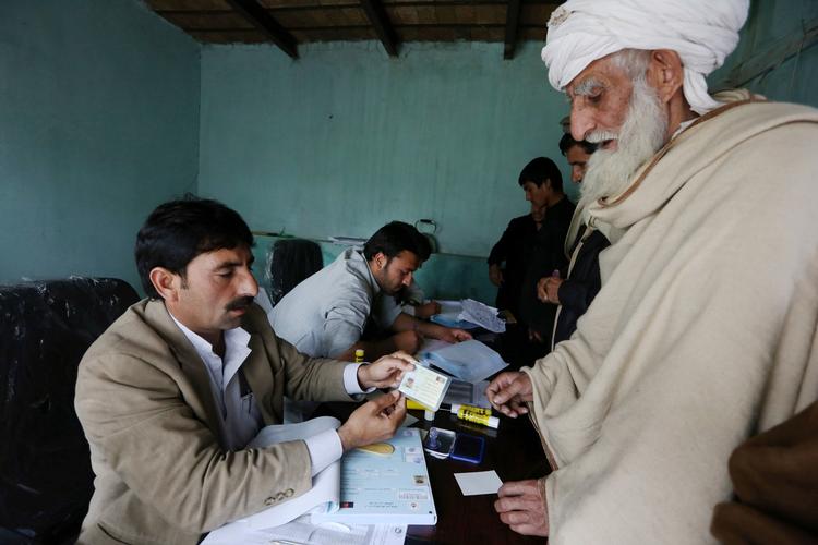 Demokrati. En afghansk mand modtager sit vælgerkort på et  valgkontor i Jalalabad. Flere Taleban-angreb præger den afghanske valgkamp. 