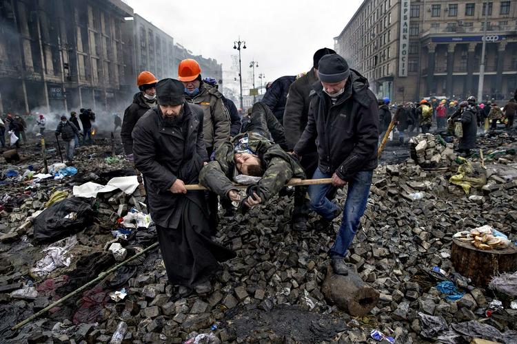 En såret bæres fra fronten under gårsdagens kampe mellem politi og aktivister. I aftes havde det voldsomme opgør kostet op mod mod 70 liv og såret flere hundrede. 