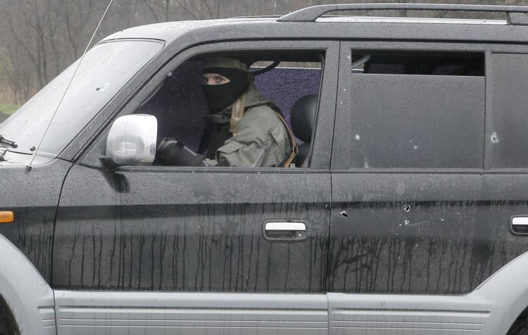 Militært. En prorussisk militant kigger ud af sin ødelagt bil i den østukrainske by Slovjansk. 