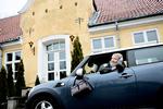 Præsteboligen. Her er Kathrine foran præsteboligen som kom med embedet iført hendes 18 år gamle Kenzo jakke, med hendes slangeskindstaske købt for 50 kroner over armen, ved siden af hendes Mini Cooper, der blev købt på fem minutter. 