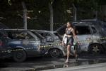 dødsfald. En kvinde passerer nogle af de udbrændte biler, der stod i vejen for optøjer og sammenstød i Rio de Janeiro natten til i dag. 