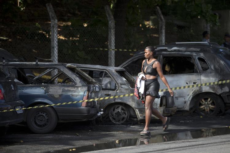 dødsfald. En kvinde passerer nogle af de udbrændte biler, der stod i vejen for optøjer og sammenstød i Rio de Janeiro natten til i dag. 