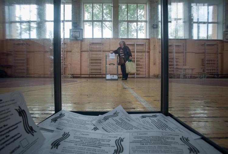 afstemning. En lokal indbygger afleverer sin stemmeseddel i en af de gennemsigtige stemmebokse på et valgsted i Luhansk. 