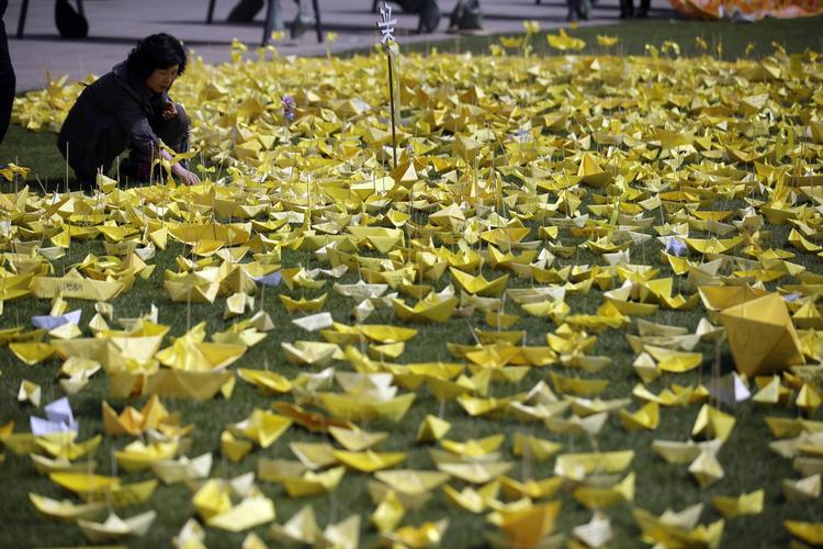 Sorg. En kvinde sætter et papirsskib ved et mindested i Seoul for de omkomne i forliset af den sydkoranske færge Sewol. 