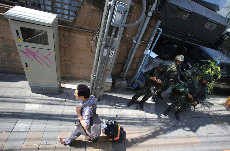 Undtagelsestilstand. En turist passerer militærfolk i Bangkoks gader torsdag den 22. maj. Byen er åben og fungerer trods uroen, siger landets turistmyndigheder. 