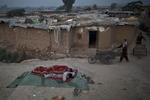 Til højre skubber unge pakistanske mænd deres grøntsagsvogne på vej mod et marked. De kommer forbi to pakistanske mænd, som sover på jorden. Mændene er flygtet med deres familier på grund af kampe mellem Taliban og militæret. 