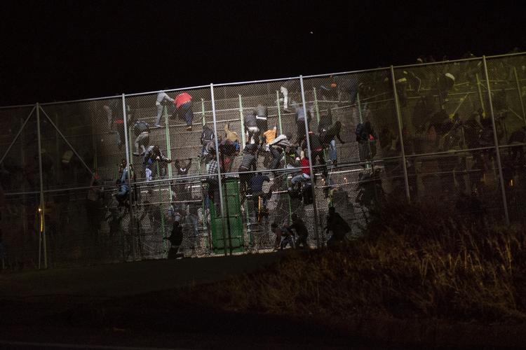 Stormløb. Desperate flygtninge forsøger tidligt i morges at kravle over hegnet til den spanske enklave Melilla. 