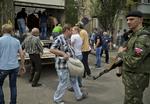 URO. Overvåget af et medlem af en russermilits i Donetsk bærer støtter sandsække til en vejspærring ud for byens lufthavn. 
